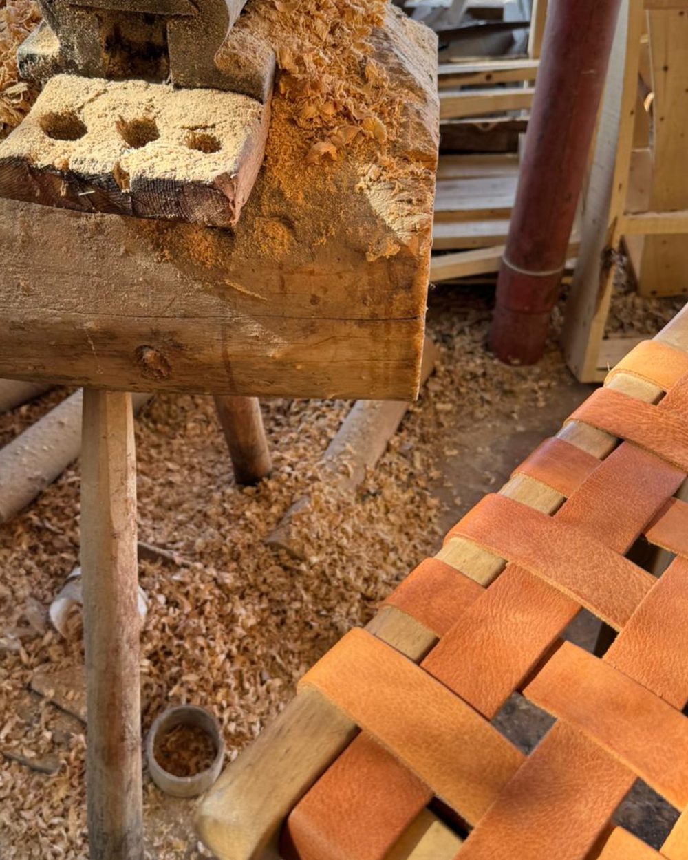 Assise en cuir tressé en cours de fabrication dans un atelier, copeaux de bois au sol