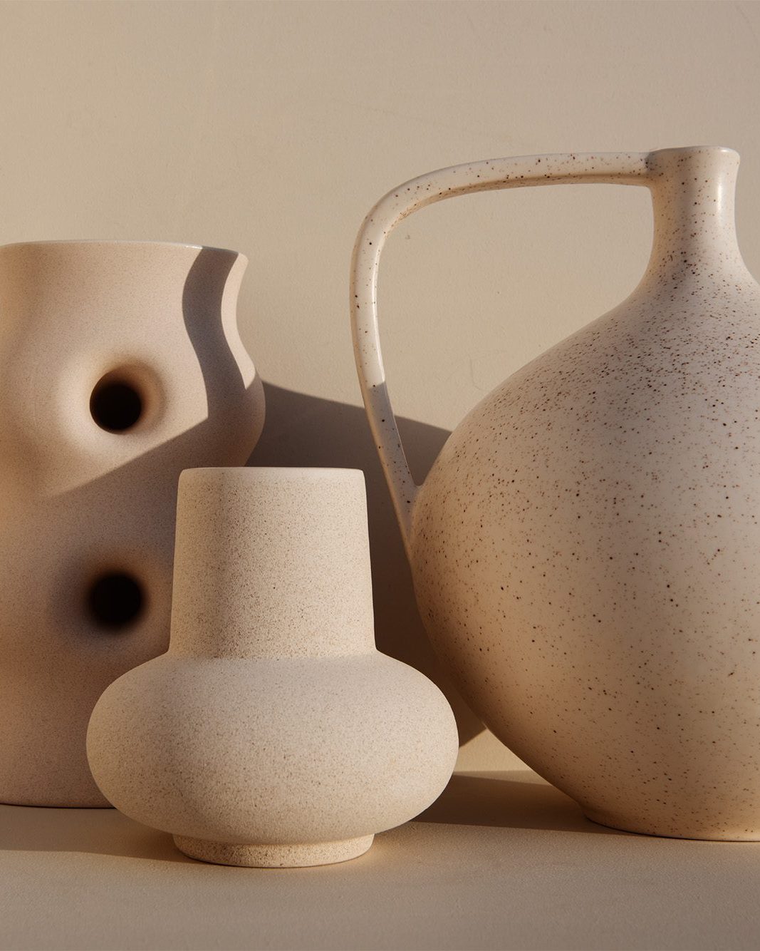 Vases en céramique crème aux formes organiques, l’un ajouré, l’autre à anse